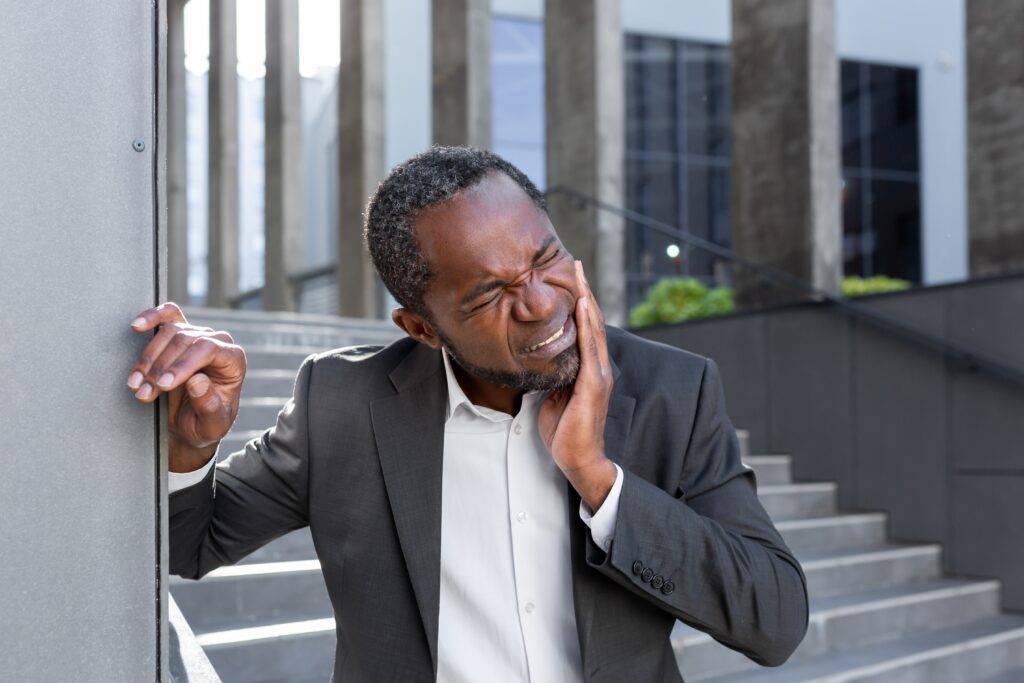suited man in a office park suffering from severe tooth pain, possible dental emergency 