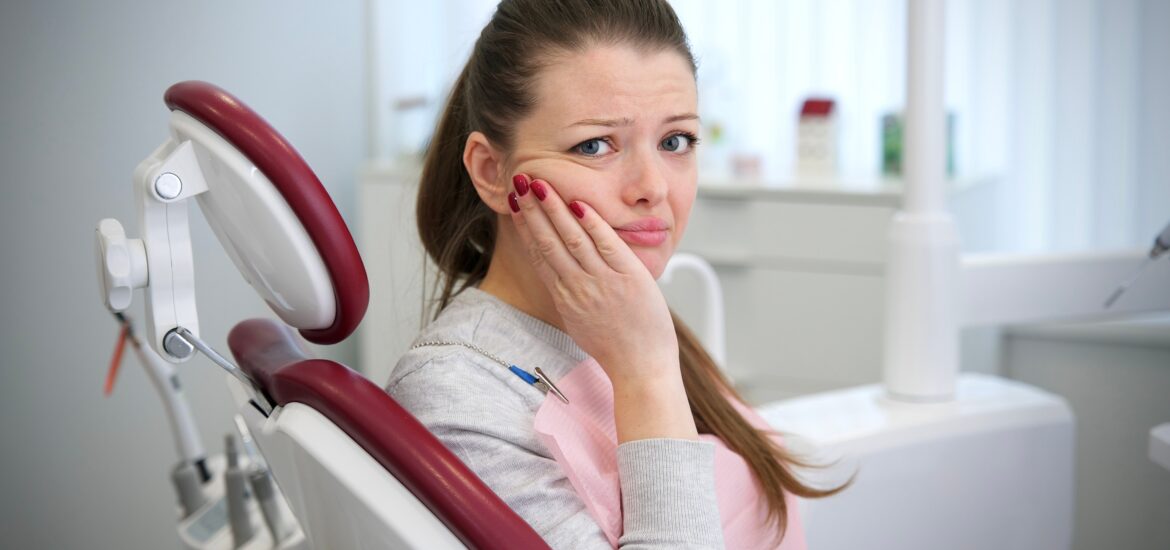 young woman in a dental chair suffering from severe tooth pain