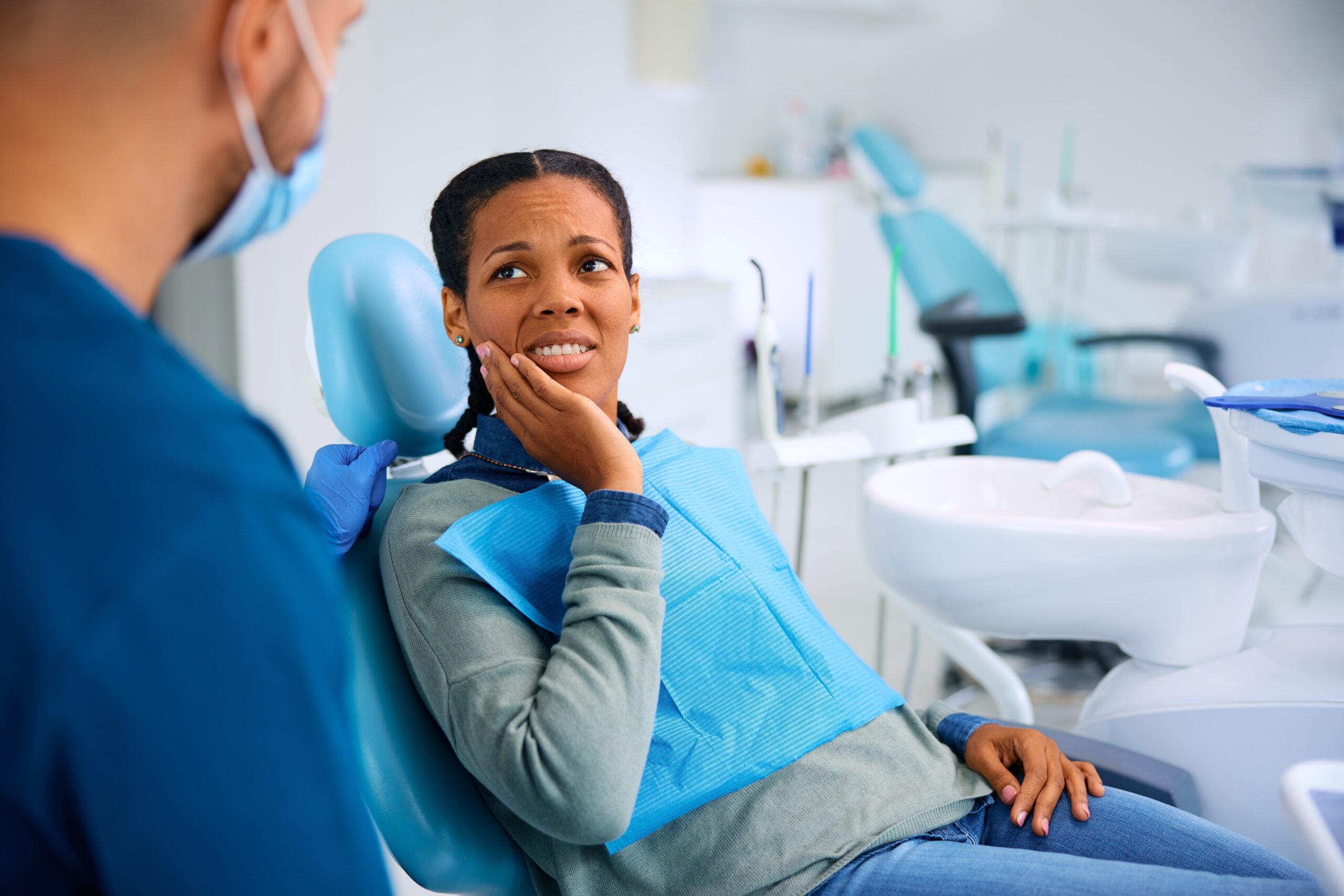African American woman in pain talking to her dentist in a modern dental practice